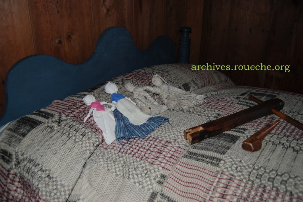 Yarn and cloth dolls displayed on the rope bed.